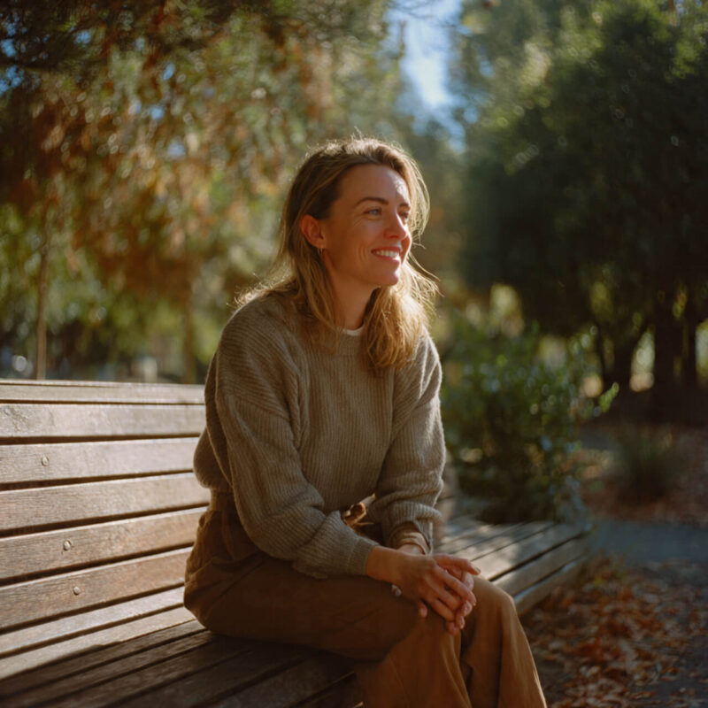 Person practicing mindfulness sitting peacefully on bench, fully present in moment, no longer living on autopilot