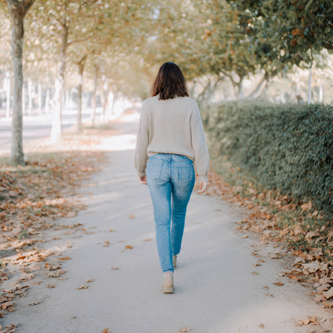 Woman practicing walking meditation on autumn tree-lined path - Buddhist wisdom for people who hate sitting still
