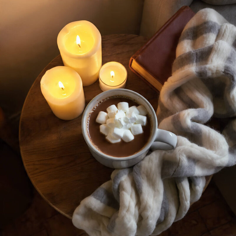 Hot chocolate with marshmallows, lit candles, and cosy blanket the perfect reward after a winter walk