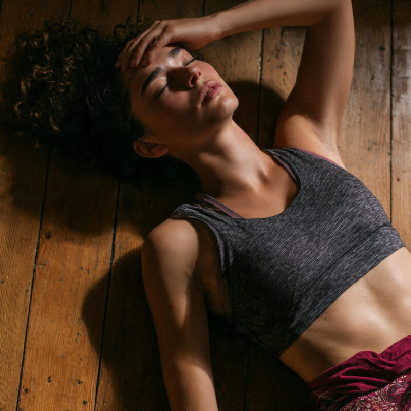 Person lying on a wooden floor in workout clothes, hand on forehead, expressing frustration and overwhelm — symbolising how it feels to hate exercise but still want to try