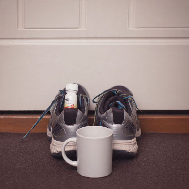 Lose motivation tips: workout shoes with vitamins and coffee mug placed as environmental reminder cues