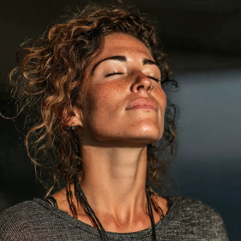 Person closing eyes and taking a deep breath in sunlight, demonstrating emotional regulation and mindful awareness — key skills in developing social intelligence
