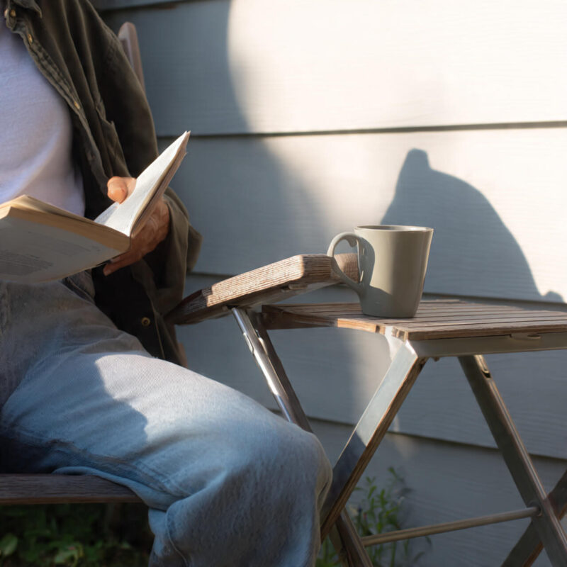 Person reading book with morning coffee demonstrating easy habits  that work for self improvement