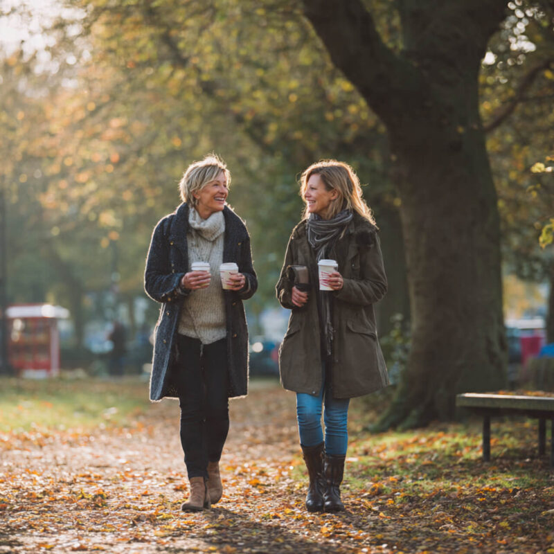 Sisters enjoying a walk and talk routine together with coffee - building walking habits through connection