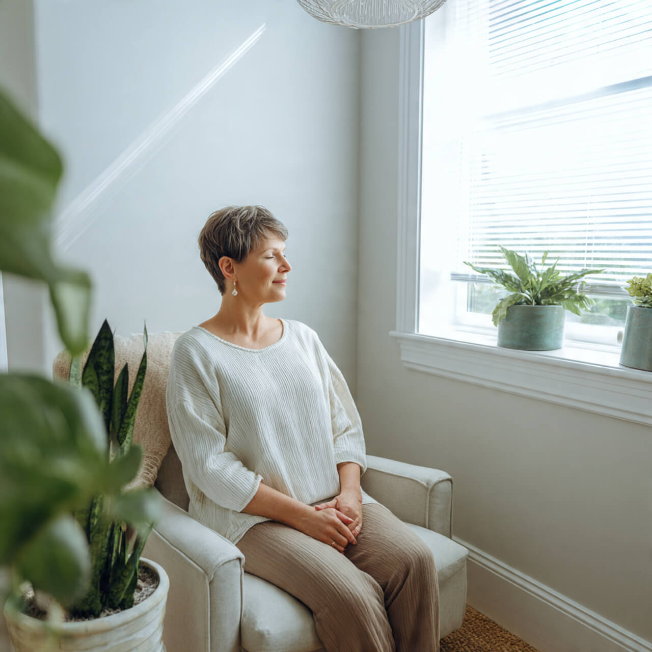 Calm woman sitting by the window practising a 5-minute morning meditation to quiet an overwhelmed mind and start the day feeling grounded and relaxed