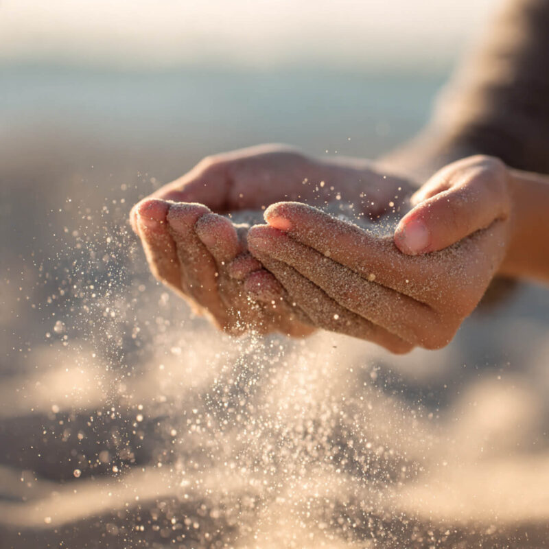 Open hands releasing sand in sunlight - letting go of painful memories and choosing to move forward