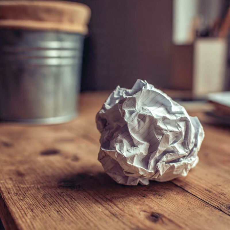 Crumpled paper list on a desk near a bin - why new year's resolutions fail by February